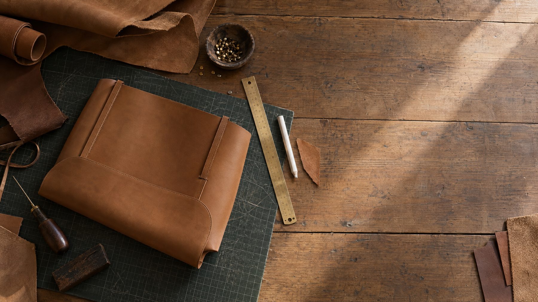 Leather panels, brass tools and a cutting mat on the Tin Bucket Mercantile workbench